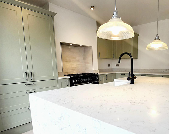 modern kitchen with green cabinets and marble countertop featuring pendant lights and a gas range ideal for 6 cooking enthusiasts