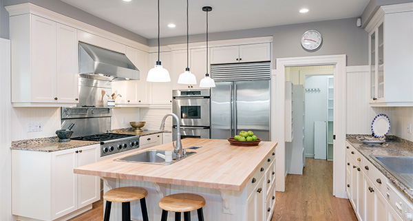 modern kitchen design with white cabinets stainless steel appliances large island featuring three bar stools and bowl of green apples
